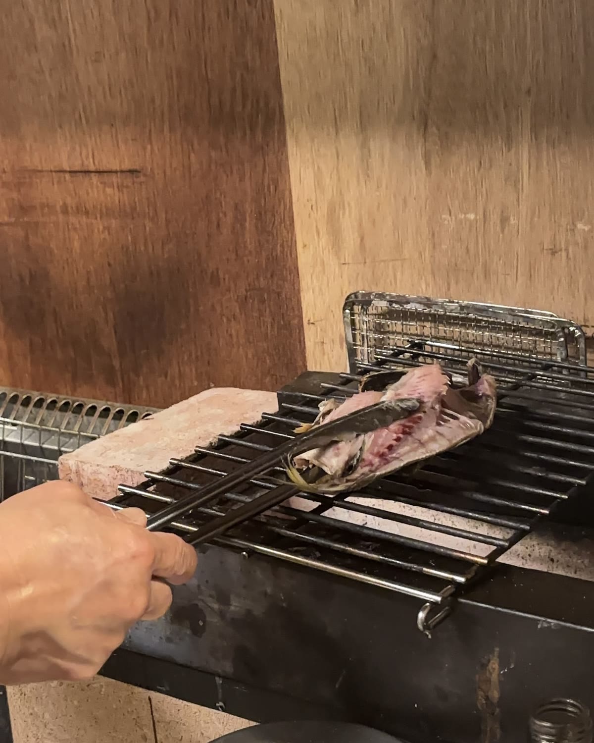 炭火の焼き台で干物を焼く店主の手元